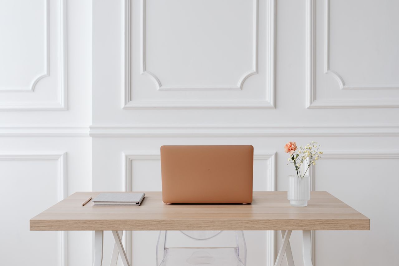 A calm, minimal desk with a laptop in warm natural light