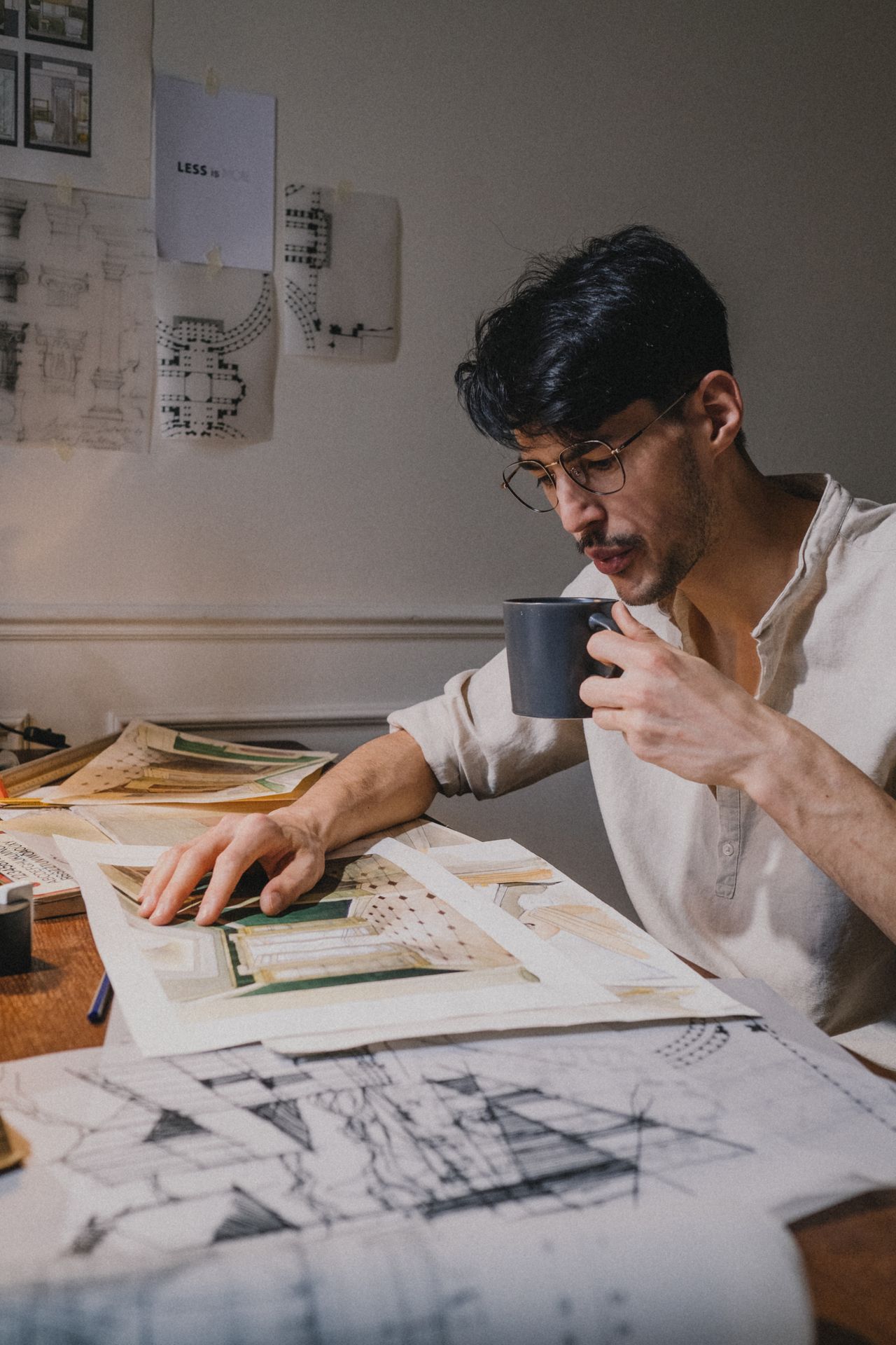 An architect reviewing drawings at a desk over coffee